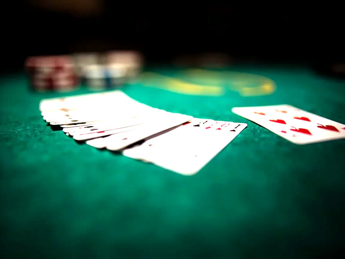 Editorial close-up photograph of a freshly dealt points-rummy hand, thirteen cards fanned in a tidy arc on a green baize table