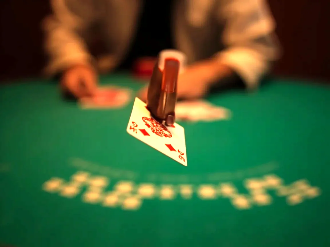 Editorial photograph of a discard decision moment, a player's hand holding two cards between thumb and forefinger above a green rummy table, a discard pile in soft focus